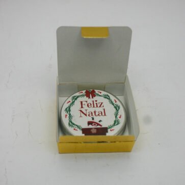 Mini vela natalina com tampa ilustrada Feliz Natal e caixa dourada metálica.